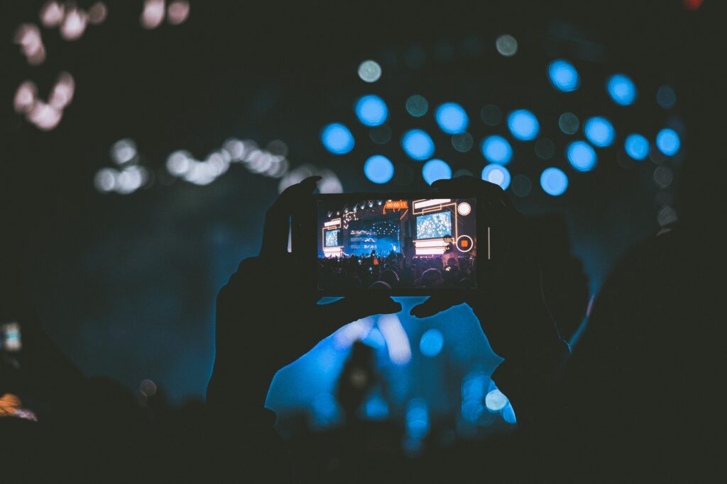 A vibrant concert scene captured through a smartphone, showcasing lively bokeh lights.